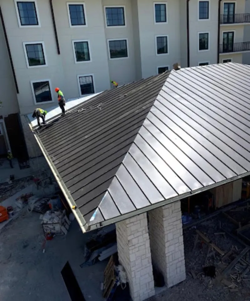 Crew installing standing seam metal roof panels on a commercial project in Pittsfield